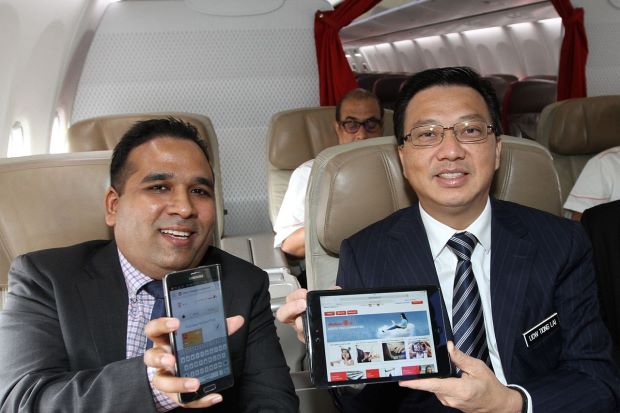 Liow (right) and Chandran trying out Malindo Air's new in-flight connectivity services on board a plane during the launch of the services and the airline's in-flight magazine at klia2, Sepang.