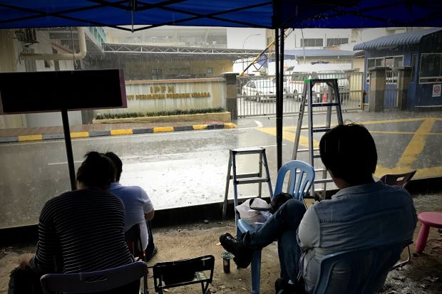 Two reporters wait outside the gates of the mortuary at Hospital Kuala Lumpur