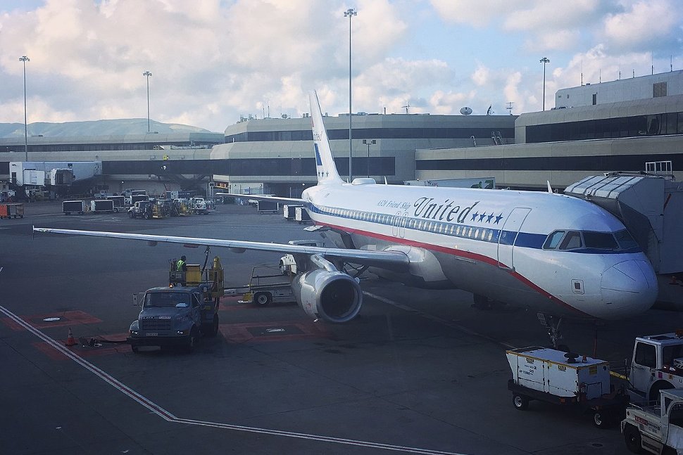A United Airlines Airbus 320 painted in retro United Friend Ship livery sits at a gate at San Francisco International Airport