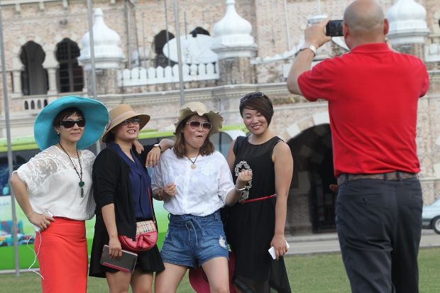 Chinese tourists posing for a photo in front  of Merdeka square in Kuala Lumpur. According to Matta, not granting visa-free entry could deter tourists from China to visit the country. - Filepic