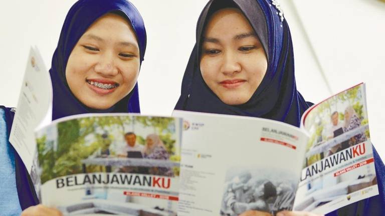 Two EPF employees looking through the ‘Belanjawanku’ guidelines pamphlet torday. – BERNAMAPIX