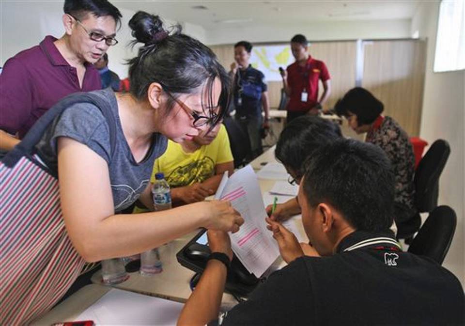 Relatives of the passengers onboard AirAsia flight QZ8501 check the plane's manifest at a crisis center set up by local authority at Juanda International Airport in Surabaya, East Java, Indonesia, Sunday, Dec. 28, 2014. The AirAsia plane with over 160 people onboard, lost contact with ground control on Sunday while flying over the Java Sea after taking off from the provincial city in Indonesia for Singapore.