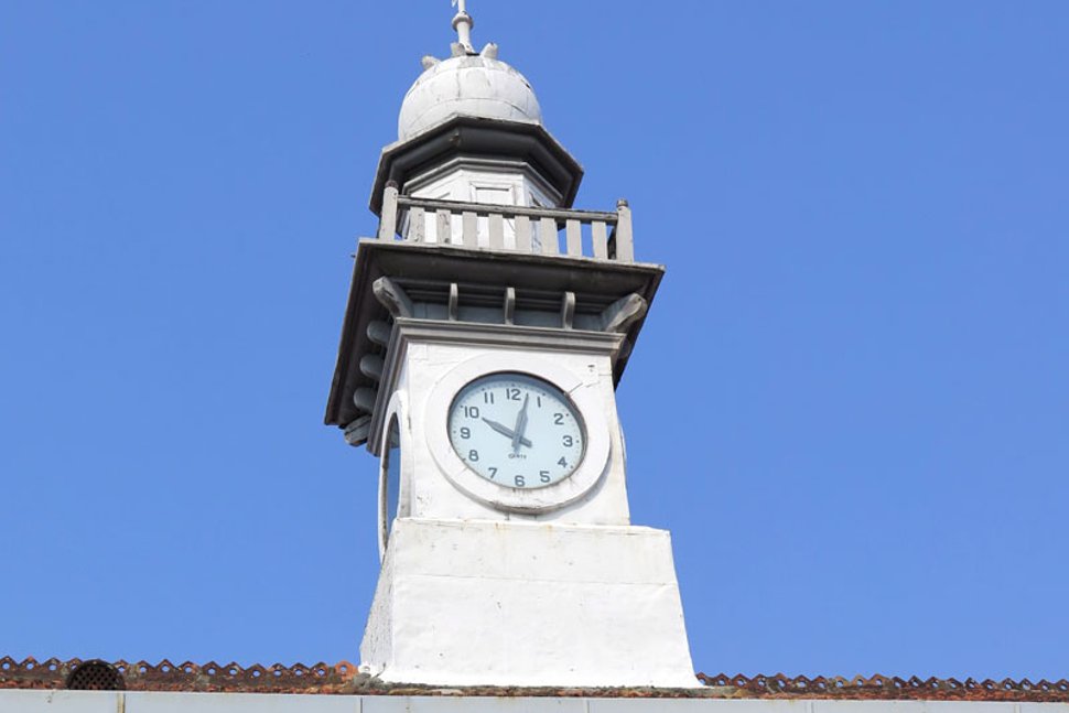 A white clock tower is erected atop the roof