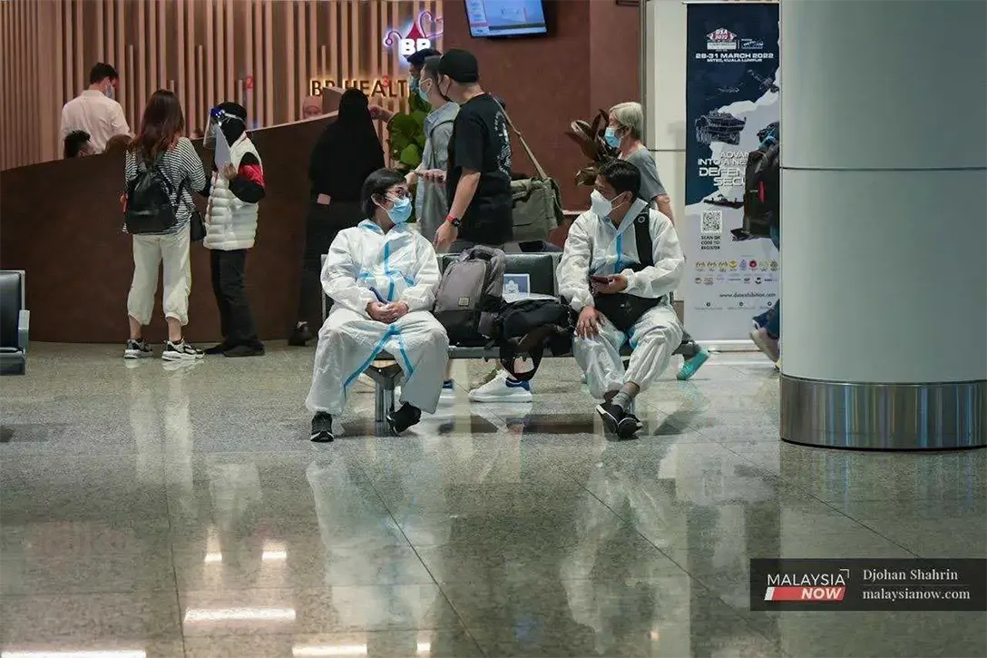 Travellers from China wearing biohazard suits sit in the waiting area at KLIA in Sepang, in this April 2022 file photo.