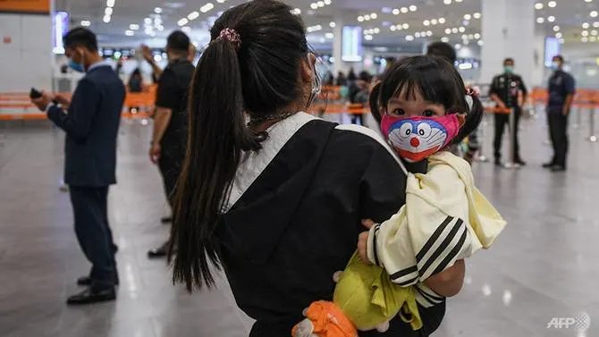 A woman carries her child, both wearing face masks, upon arrival at the Kuala Lumpur International Airport 2 (KLIA2) in Sepang on Jan 29, 2020. (Photo: AFP/Mohd RASFAN)