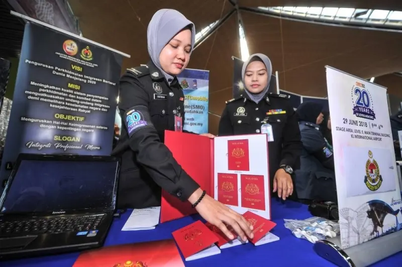 Immigration personnel (from left) Syafiqhah Munirah and Hajah Nor Atiza exhibit new Malaysian passports at the immigration exhibition booth during KLIA's 20th Anniversary Celebration at KLIA in Sepang June 29, 2018. — Picture by Shafwan Zaidon