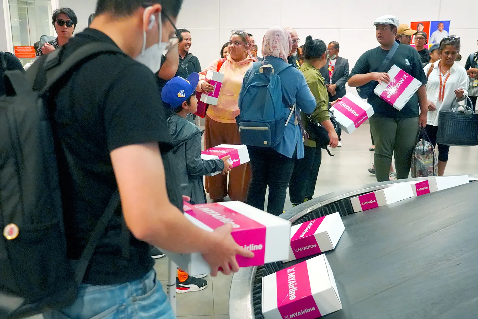 Passengers receiving their giftboxes that was placed on the luggage carousel