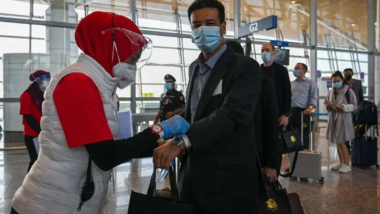 A health officer (left) installs a ribbon to a passenger in Kuala Lumpur International Airport (KLIA) in Sepang, under the vaccinated travel lane for border crossing passengers in Sepang, on November 29, 2021. AFP