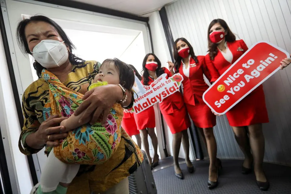 Stewardesses welcome a woman and toddler, as they disembark from an airplane from Jakarta, Indonesia at Kuala Lumpur International Airport 2 (KLIA2), as the country reopens its borders fully to allow entry without quarantine for visitors vaccinated against coronavirus disease (COVID-19) in Sepang, Selangor, Malaysia, April 1, 2022. REUTERS/Hasnoor Hussain