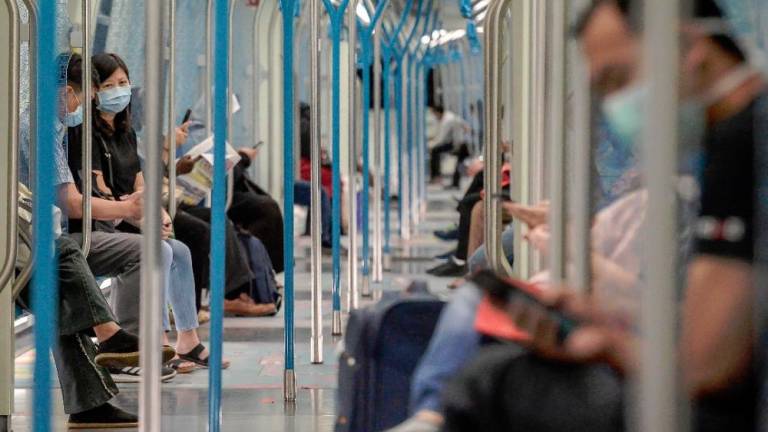 Passengers with face masks maintain social distancing while travelling on the MRT during the MRCO period. — Sunpix by Adib Rawi Yahya