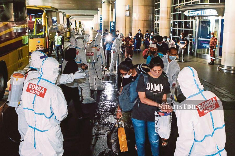 Fire and Rescue Department personnel attending to overseas returnees at the Kuala Lumpur International Airport on Saturday. PIC BY LUQMAN HAKIM ZUBIR