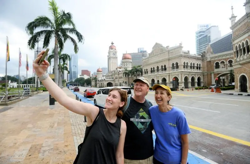 Back again: Tourists (from left) Hannah Lins, Dennis Lins and Lori Lins from the US taking a wefie shot with the background of the Sultan Abdul Samad in Kuala Lumpur (11/6/2022). —AZHAR MAHFOF/The Star
