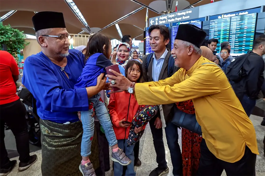 Two grandfathers take turn in embracing their niece, after their family returned home at the Kuala Lumpur International Airport. - BERNAMA PIC