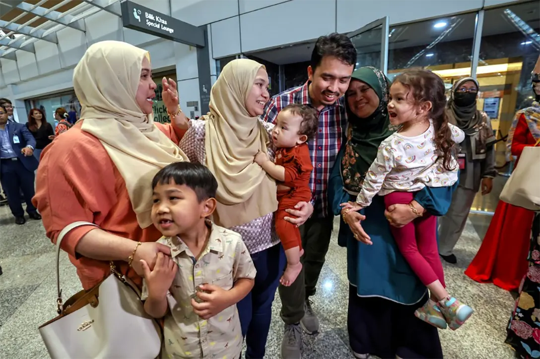Mohd Faiz Firdaus, wife Farihin Rosni and their children are welcomed home by their family members at the Kuala Lumpur International Airport. - BERNAMA PIC