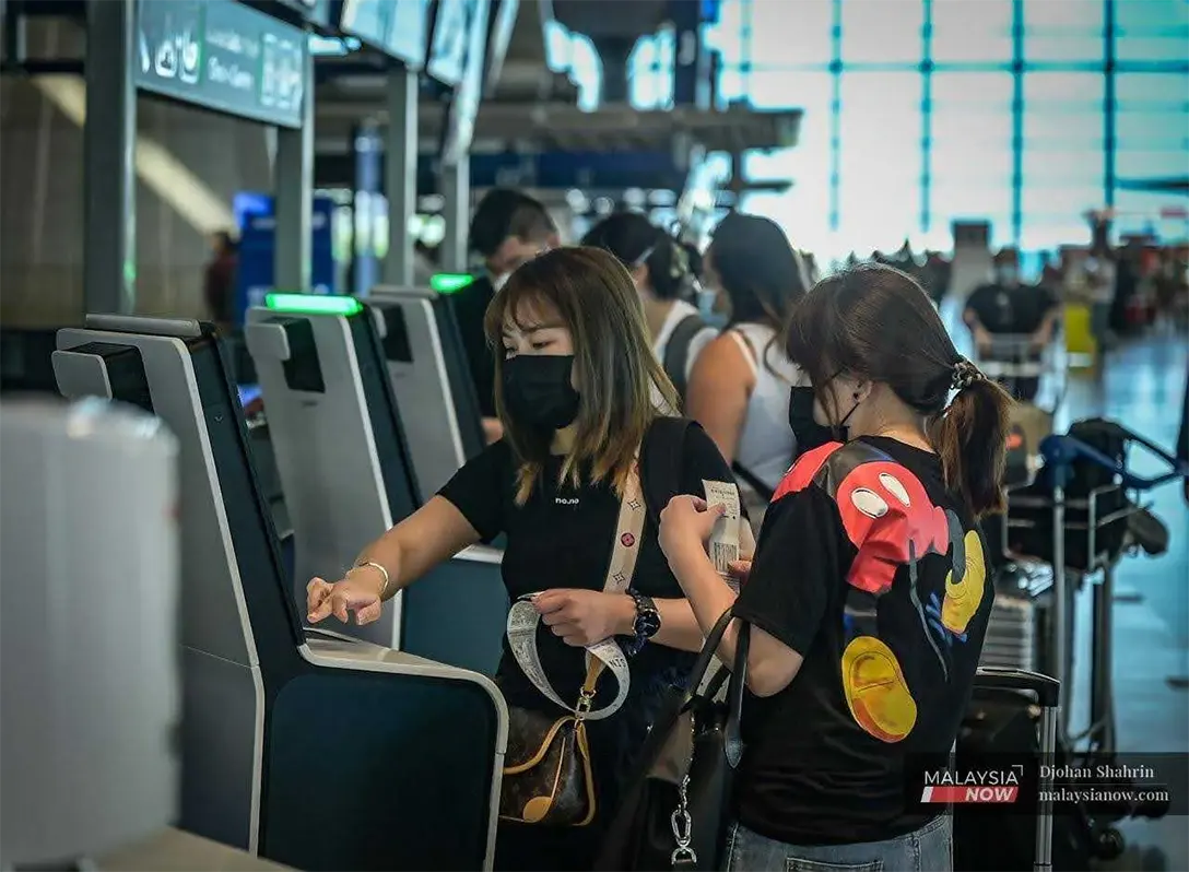 Travellers check in at a kiosk at KLIA in Sepang in this file photo.