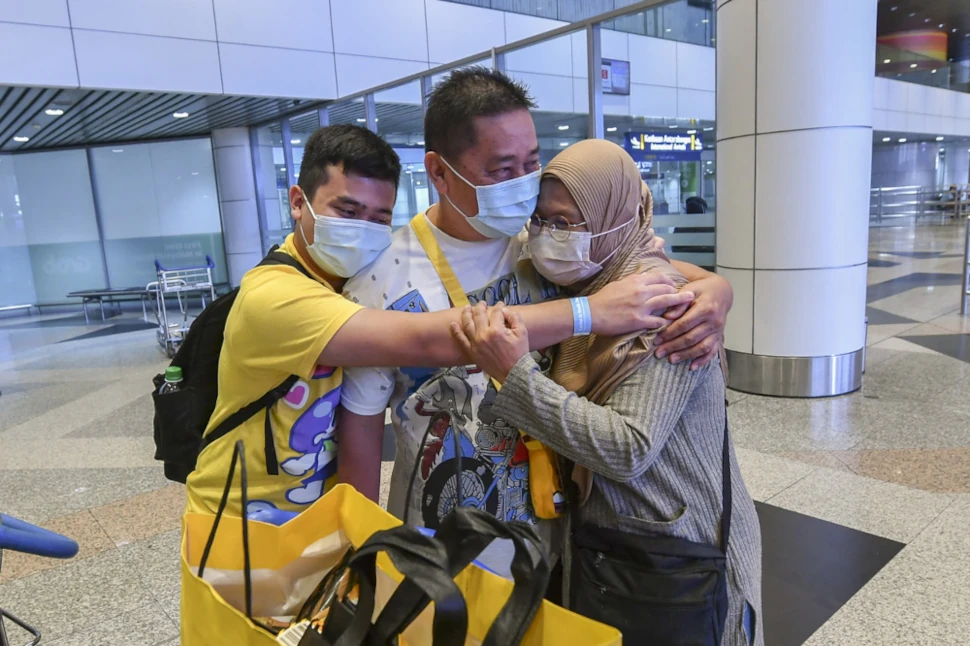 Abdul Jalal Mohd Tahir, 58, is hugged by his wife, Khadijah Ahmad, 54, and their son Mikayl Abdul Jalal, 22 after the two arrived from Singapore at the Kuala Lumpur International Airport, November 29, 2021. — Bernama pic